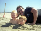 Grandpa with Cameron  and Logan buried in sand, mothers upset (photo by Coleen).
